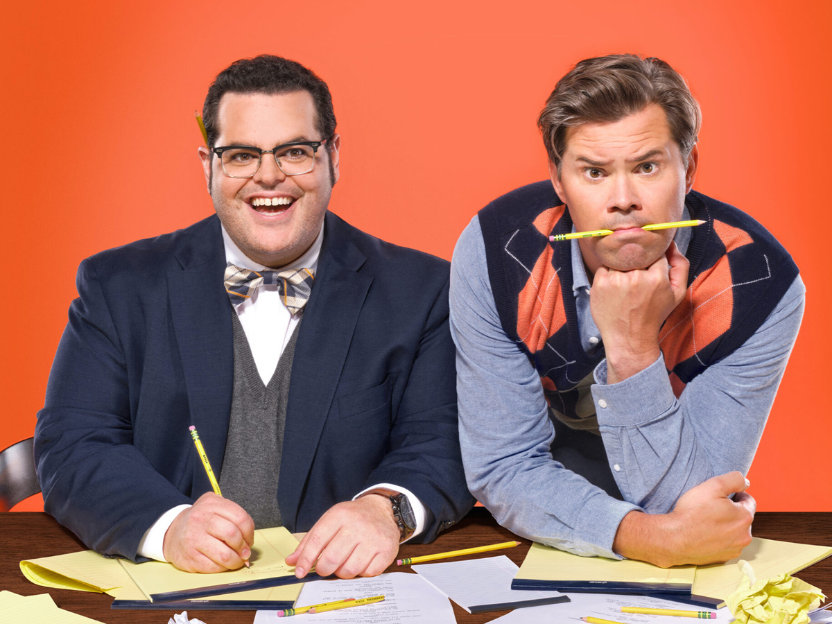 Josh Gad and Andrew Rannells sit at a table writing