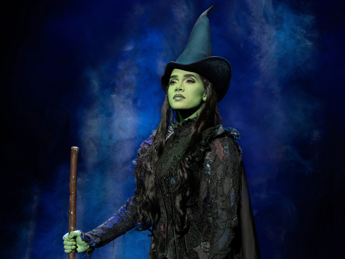 Elphaba dramatically stands holding her broom in Wicked on Broadway
