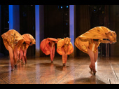 The lionesses' headpieces evoke the urns carried on the heads of African tribeswomen.